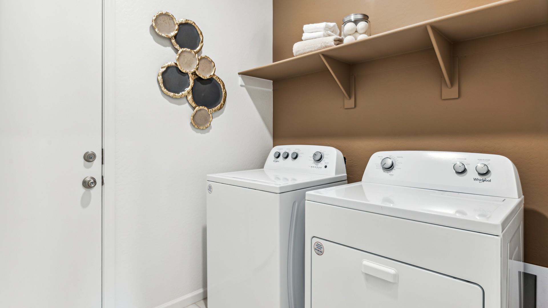 A laundry room featuring a washer and dryer, neatly arranged with ample space for laundry tasks and storage.
