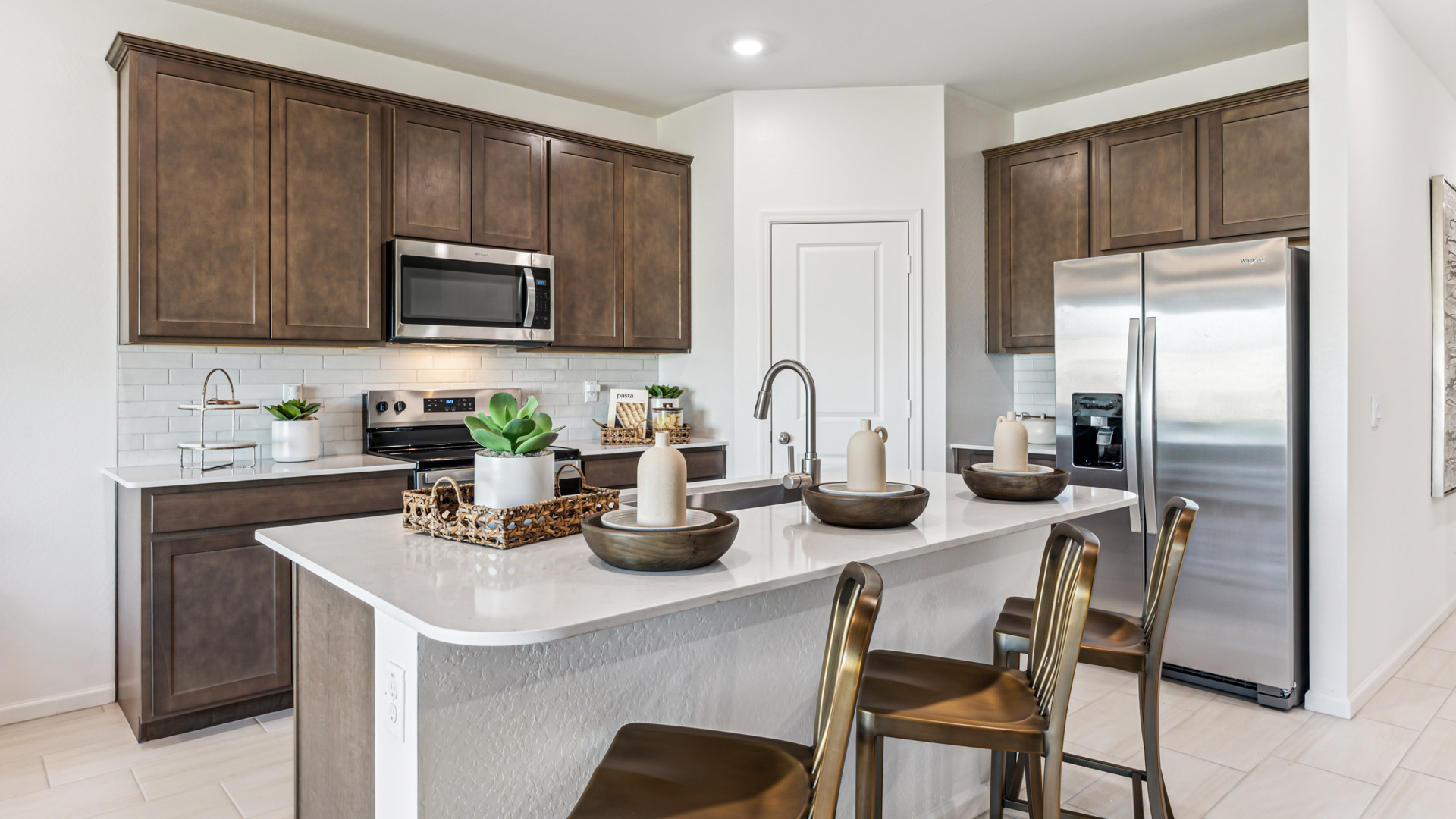 Bright and spacious kitchen with quartz countertops, stainless steel appliances, and an island with bar seating.