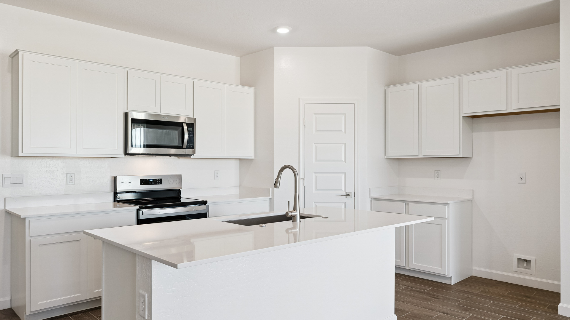 Bright and spacious kitchen with quartz countertops, stainless steel appliances, and an island with bar seating.