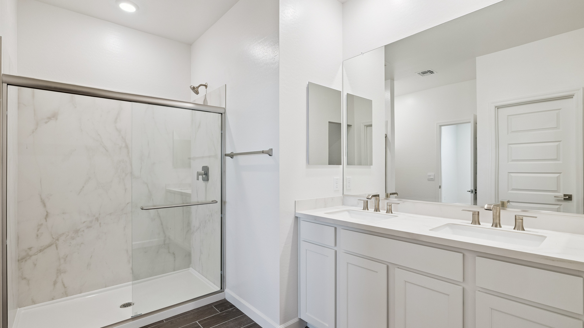 Modern primary bathroom with double vanities, quartz countertops with a walk-in shower and a walk-in closet.