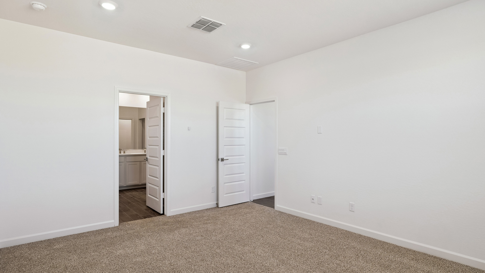 A spacious primary bedroom emphasizing open space and natural lighting.