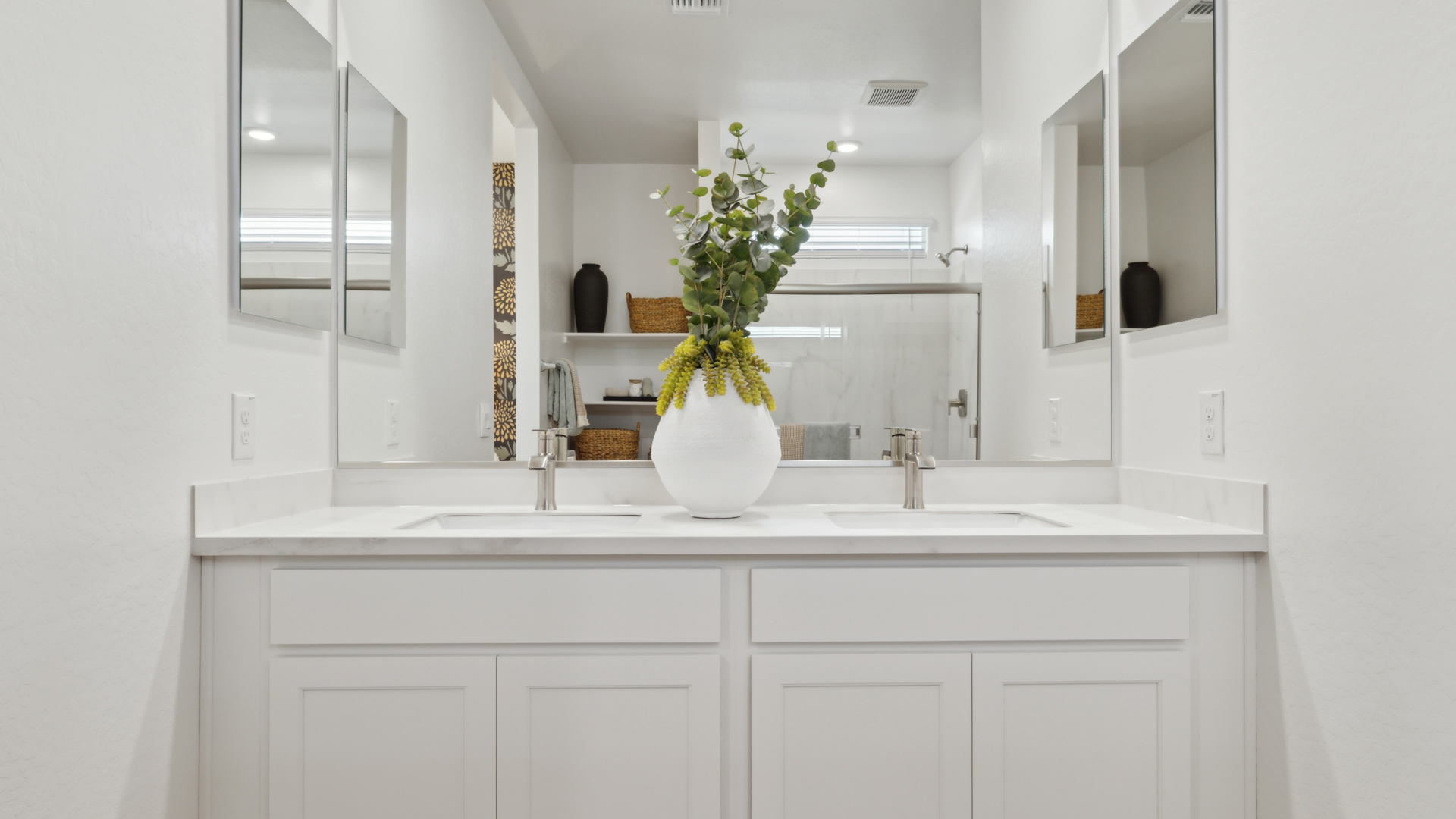 Modern primary bathroom with double vanities, countertops with a walk-in shower and a walk-in closet.