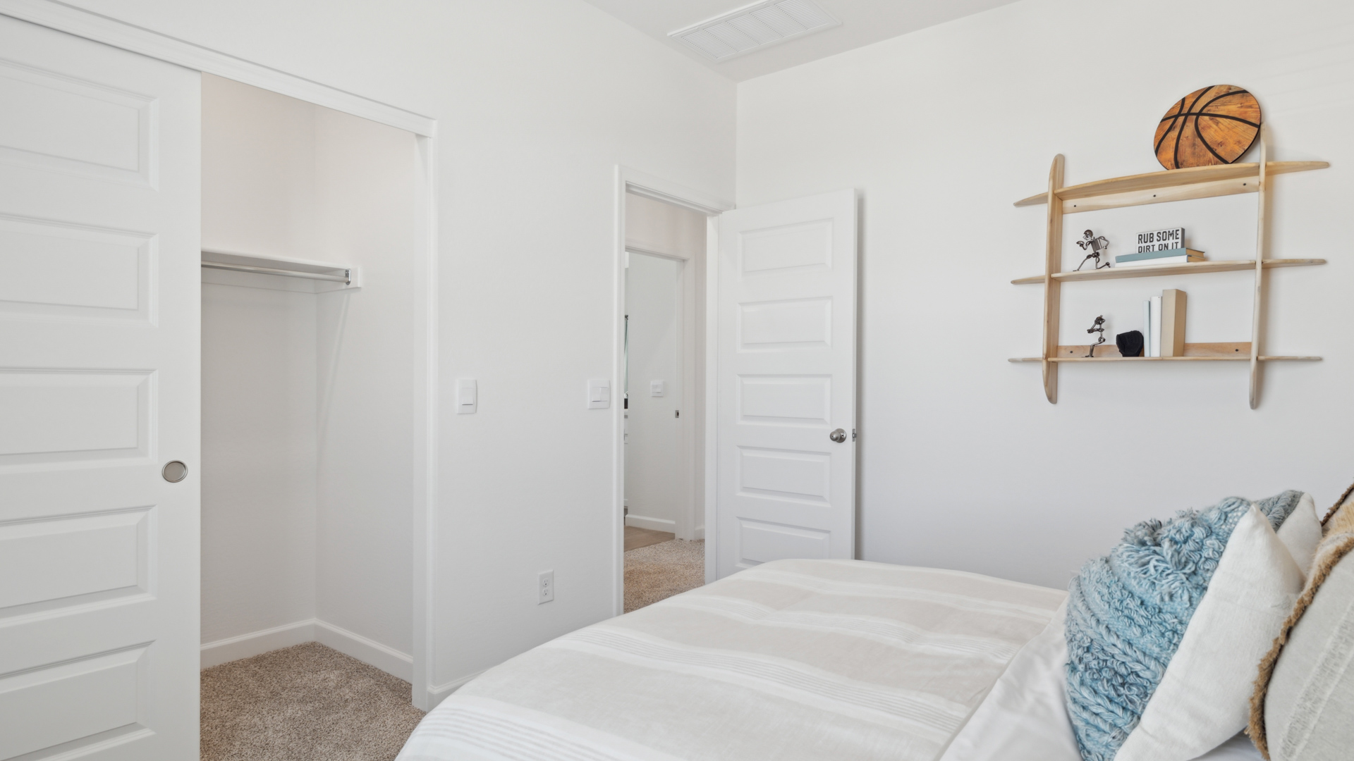 A vibrant kids' bedroom showcasing a neatly made bed, a stylish dresser, and a playful painting that adds charm.