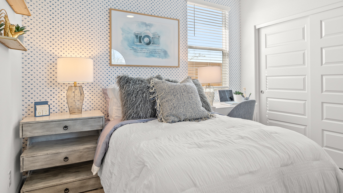 A vibrant kids' bedroom showcasing a neatly made bed, a stylish dresser, and a playful painting that adds charm.