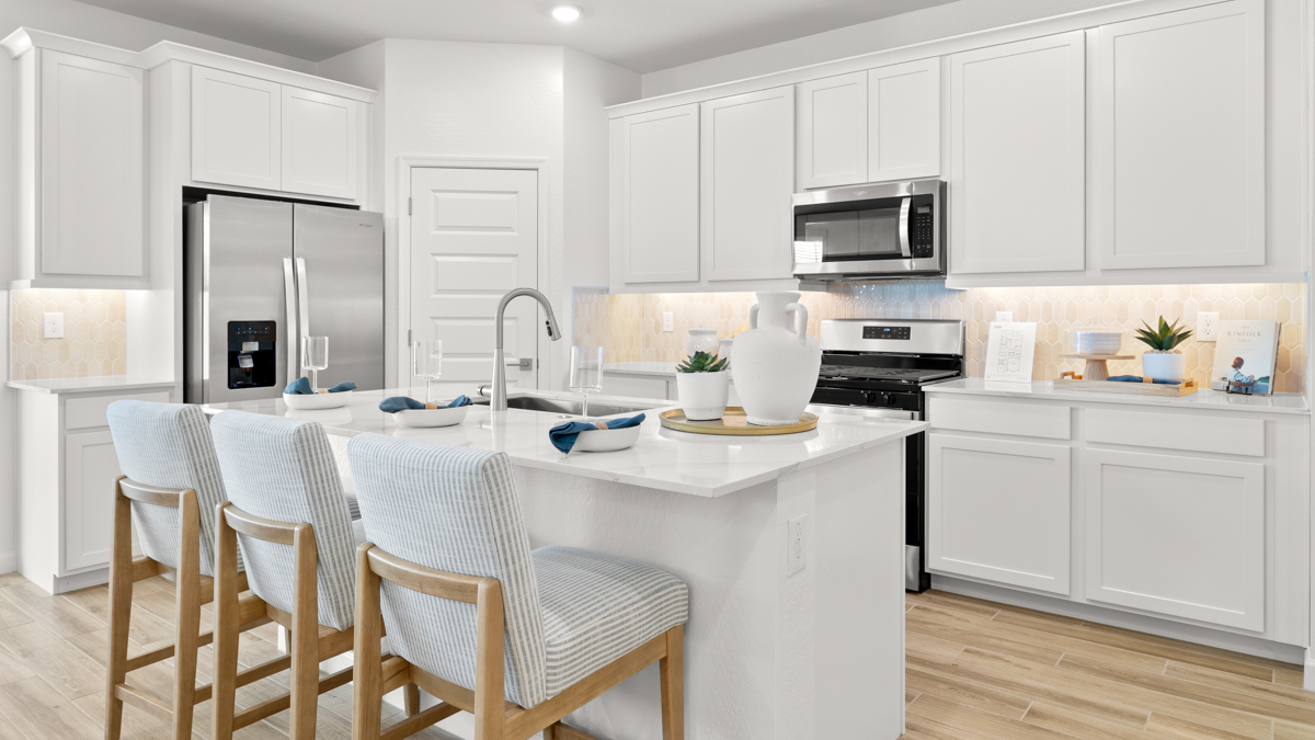 Bright and spacious kitchen with countertops, stainless steel appliances, and an island with bar seating.