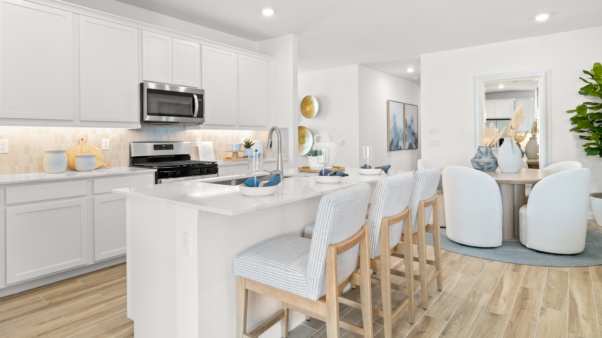 Bright and spacious kitchen with countertops, stainless steel appliances, and an island with bar seating.
