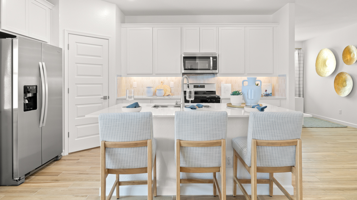Bright and spacious kitchen with countertops, stainless steel appliances, and an island with bar seating.