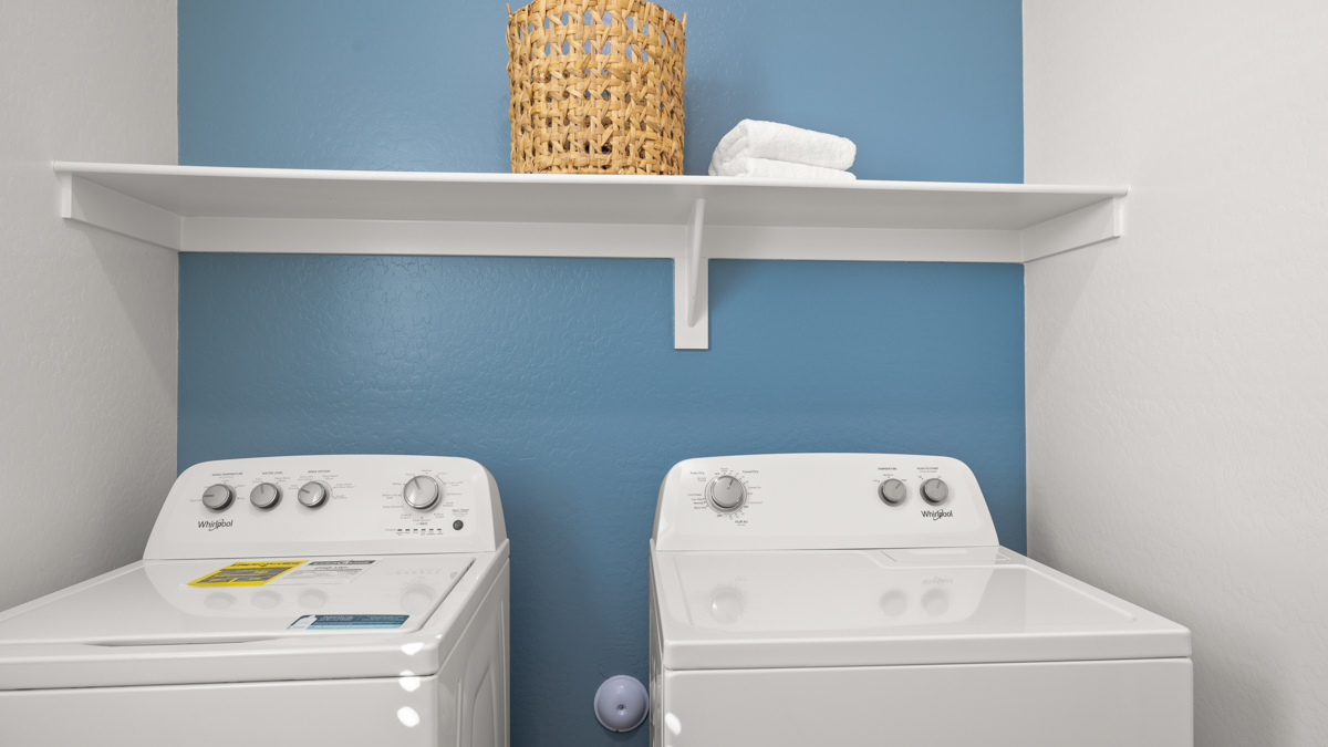 A laundry room featuring a washer and dryer, neatly arranged with ample space for laundry tasks and storage.