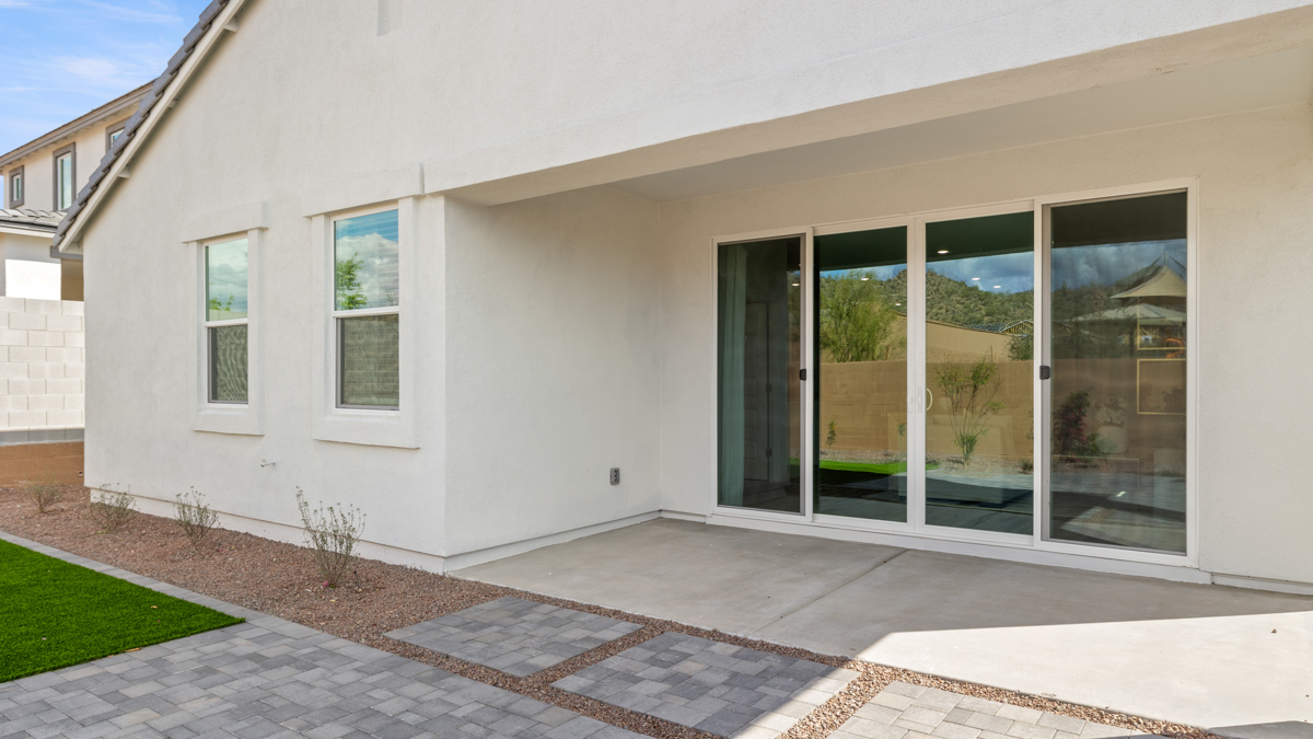 Outdoor covered patio with seating area overlooking a well-maintained lawn, perfect for relaxation.