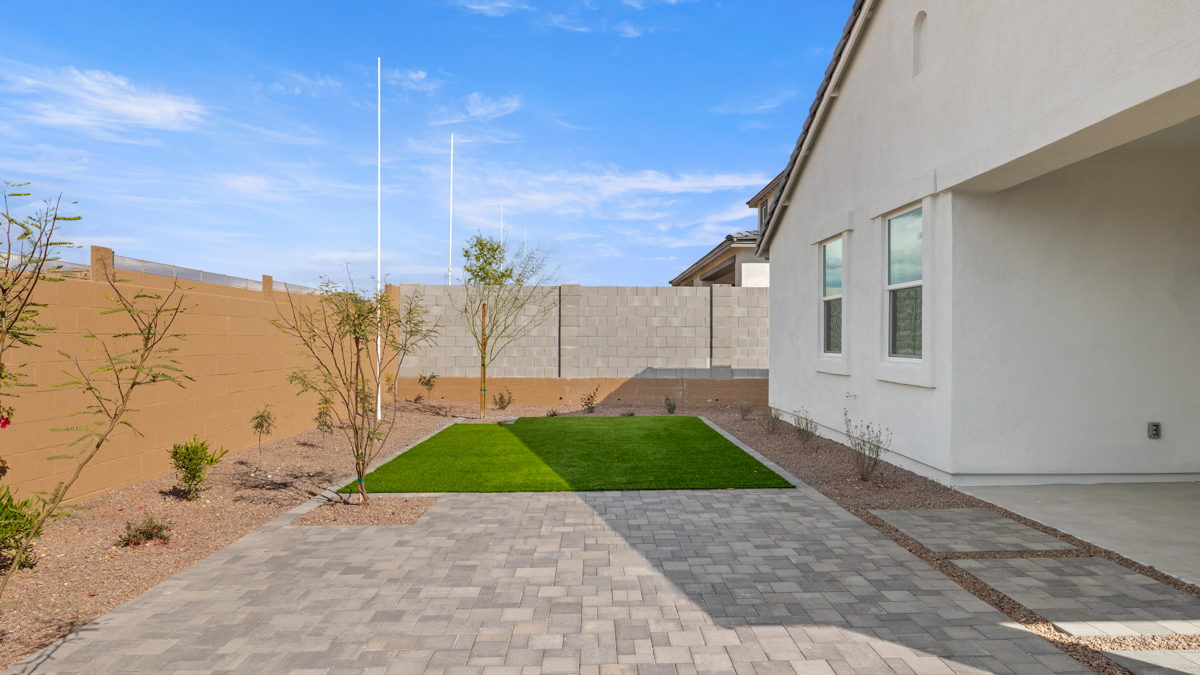 Outdoor covered patio with seating area overlooking a well-maintained lawn, perfect for relaxation.