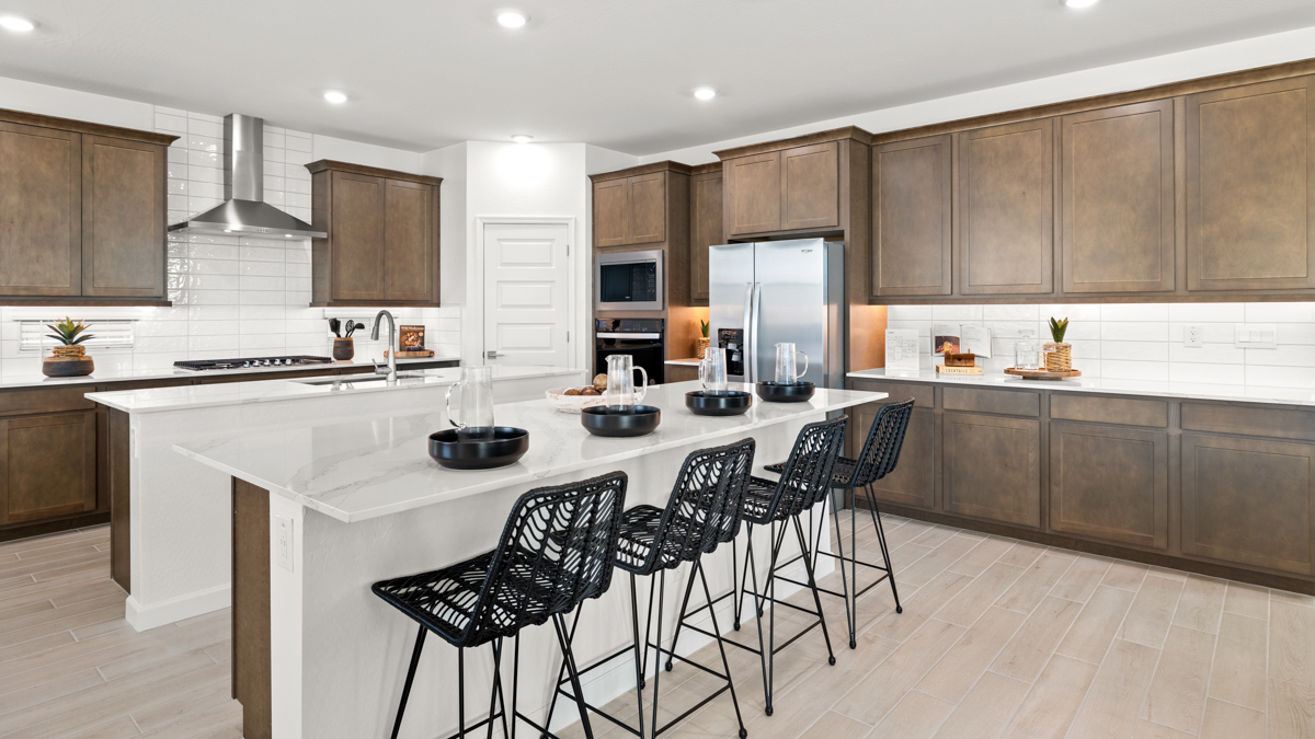 Bright and spacious kitchen with quartz countertops, stainless steel appliances, and an island with bar seating.