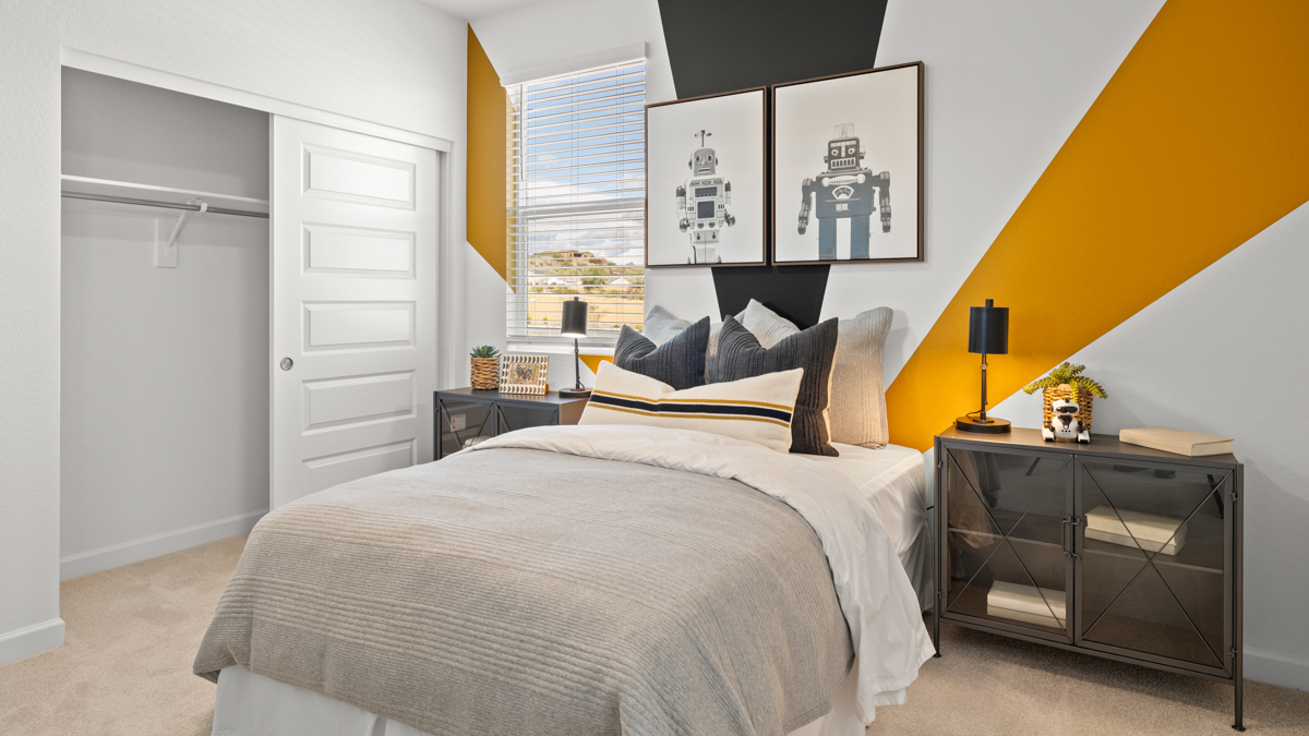 .A vibrant kids' bedroom showcasing a neatly made bed, a stylish dresser, and a playful painting that adds charm.