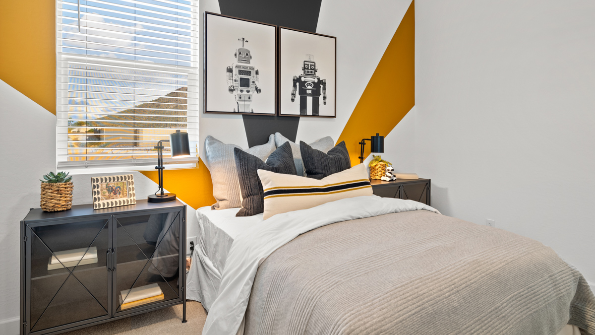 A vibrant kids' bedroom showcasing a neatly made bed, a stylish dresser, and a playful painting that adds charm.