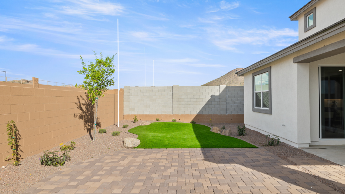 Outdoor covered patio with seating area overlooking a well-maintained lawn, perfect for relaxation.
