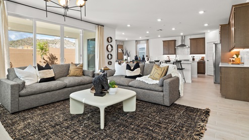 Great Room with white modern coffee table, large gray couches, and view of kitchen behind.