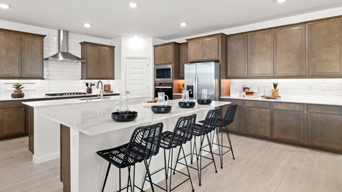Kitchen with medium brown cabinets, quartz countertops, white tile backsplash, with corner pantry.