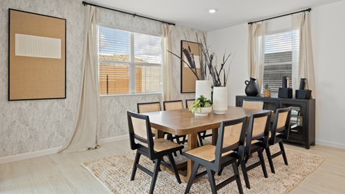 Dining Room with accent wall, long flowy beige curtains, and wooden table that seats eight.