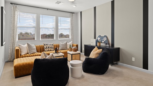 Loft with black and gray striped accent wall, vintage yellow lounge couch, black beanbag chairs with three large windows looking into backyard.