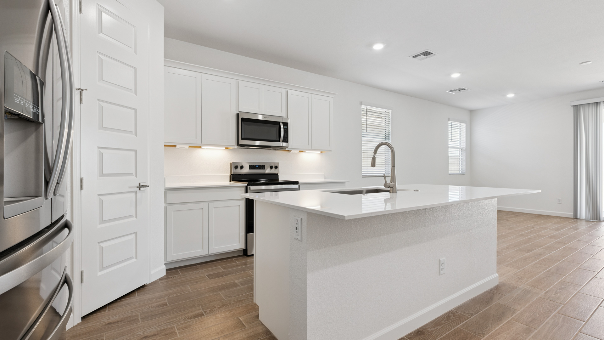 Bright and spacious kitchen with quartz countertops, stainless steel appliances, and an island with bar seating.