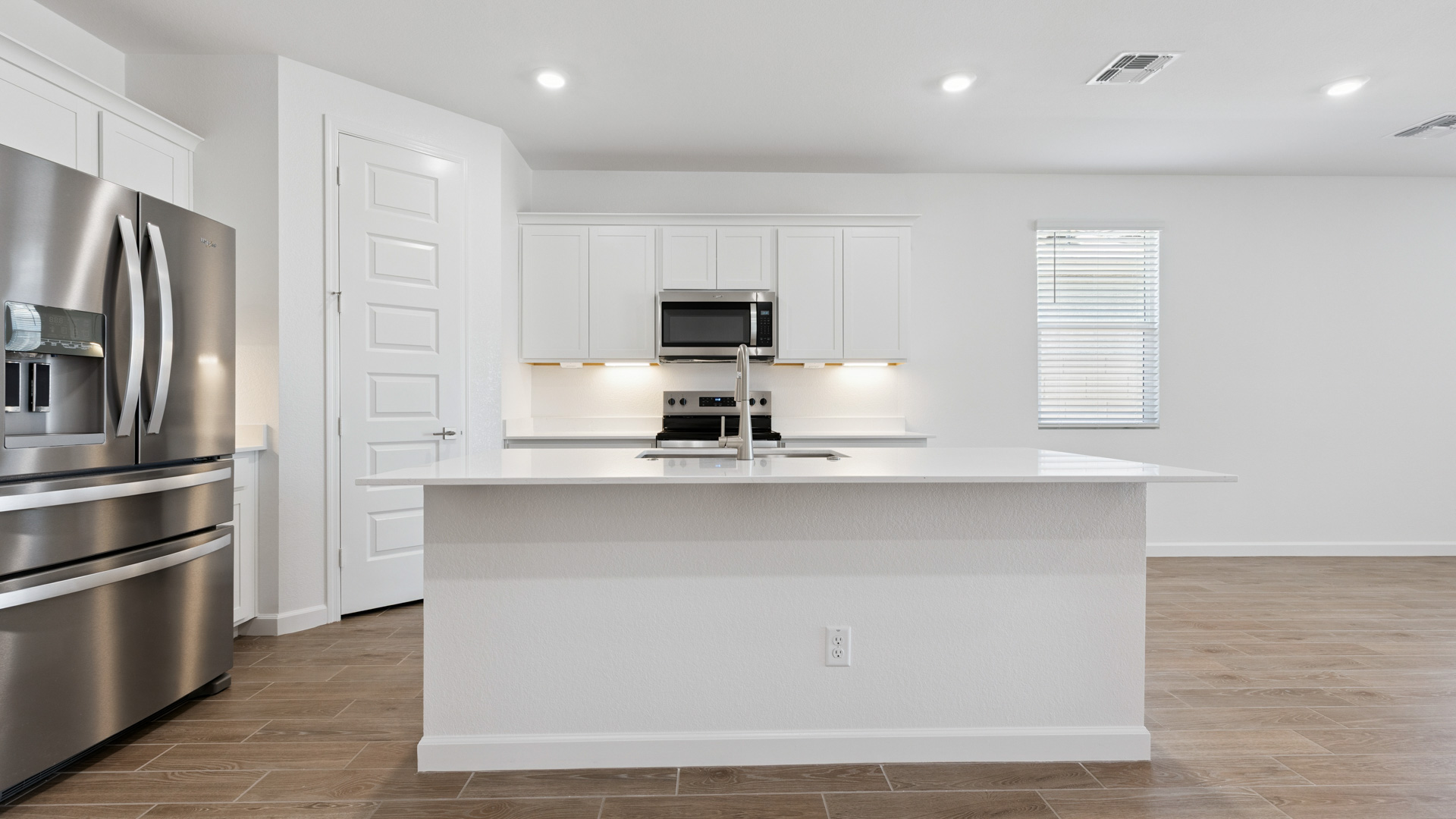 Bright and spacious kitchen with quartz countertops, stainless steel appliances, and an island with bar seating.