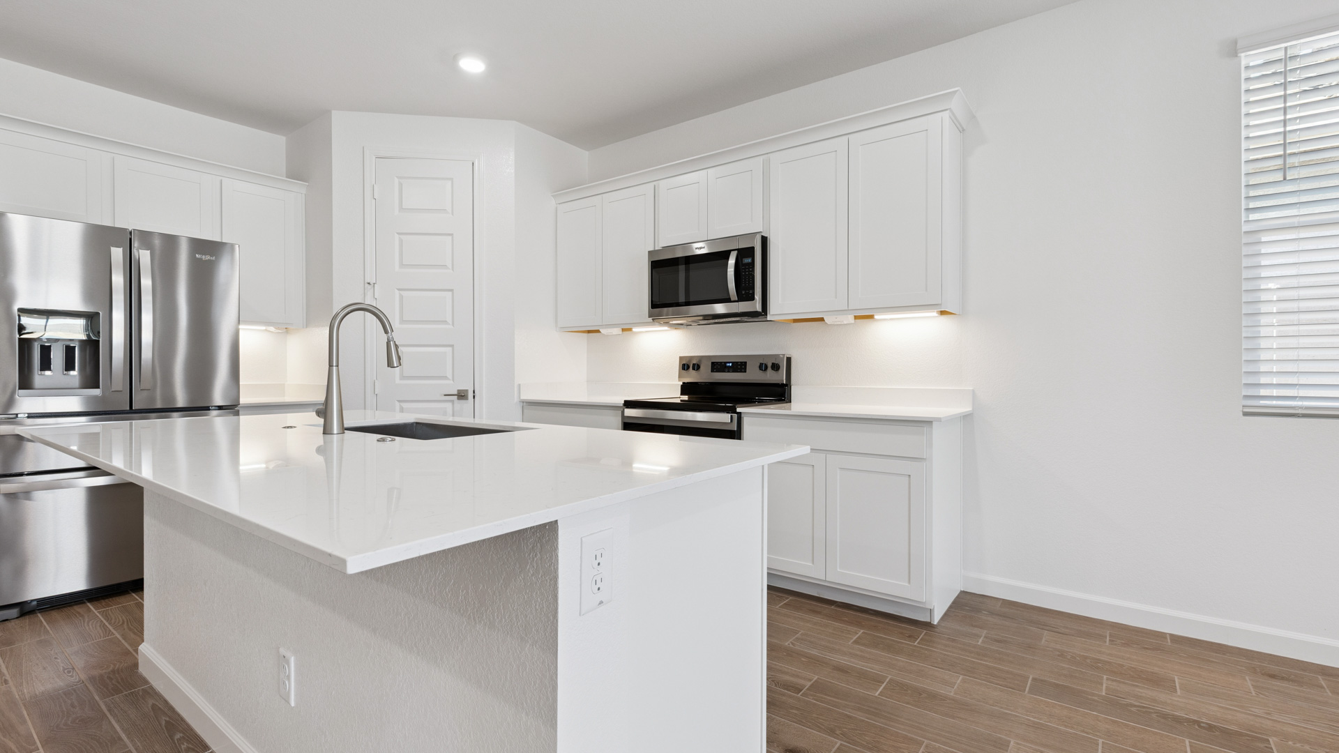 Bright and spacious kitchen with quartz countertops, stainless steel appliances, and an island with bar seating.