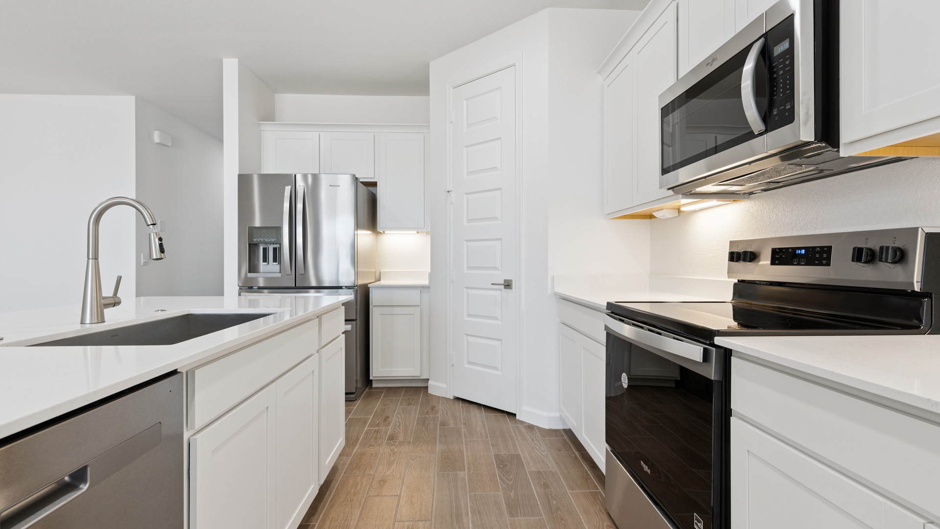 Bright and spacious kitchen with quartz countertops, stainless steel appliances, and an island with bar seating.