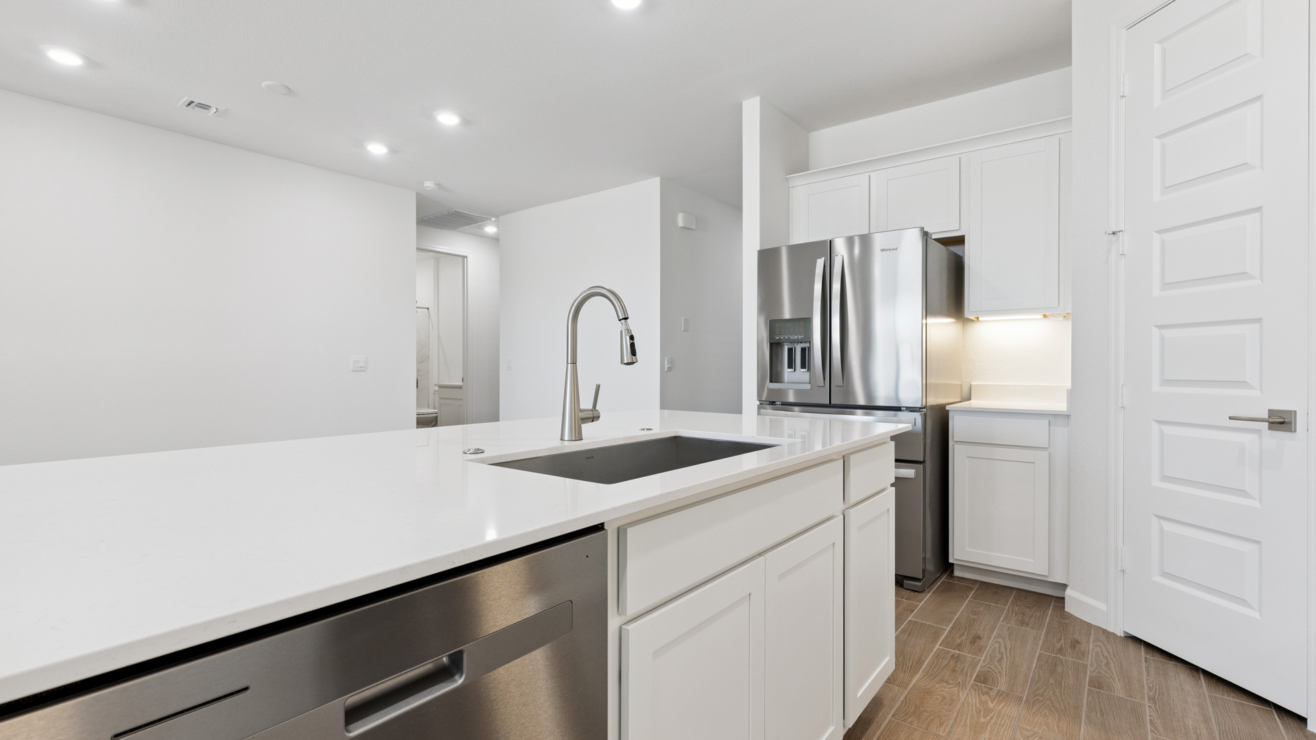 Bright and spacious kitchen with quartz countertops, stainless steel appliances, and an island with bar seating.