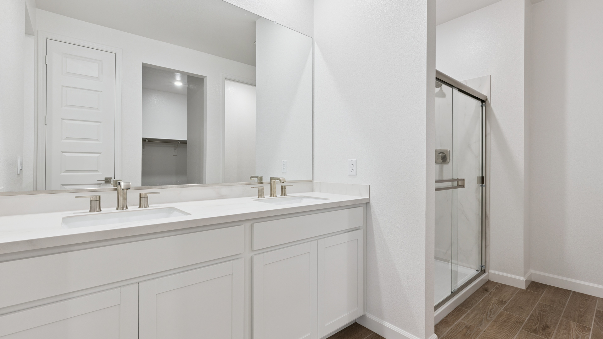 Modern primary bathroom with double vanities, quartz countertops with a walk-in shower and a walk-in closet.