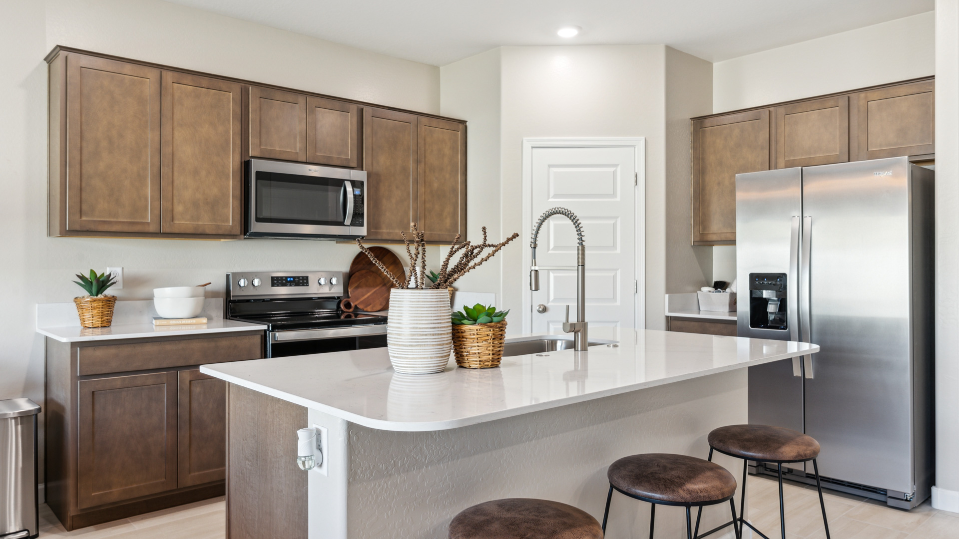 Bright and spacious kitchen with countertops, stainless steel appliances, and an island with bar seating.