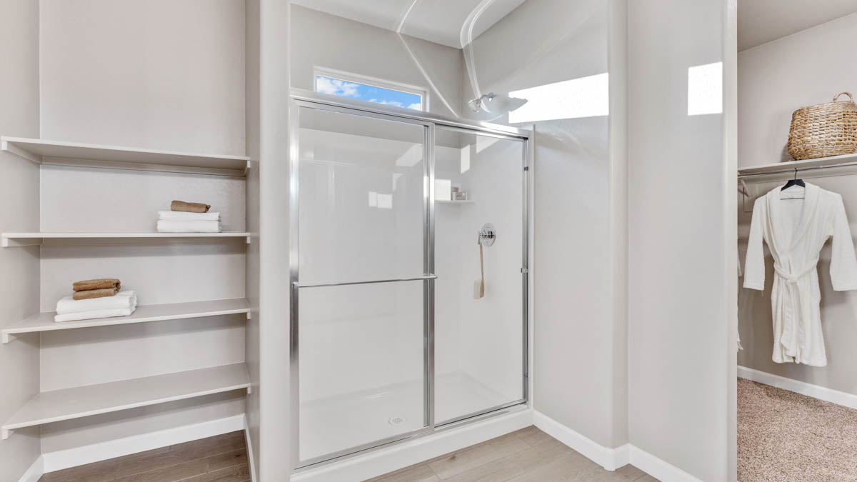 Modern primary bathroom with double vanities, quartz countertops with a walk-in shower and a walk-in closet.