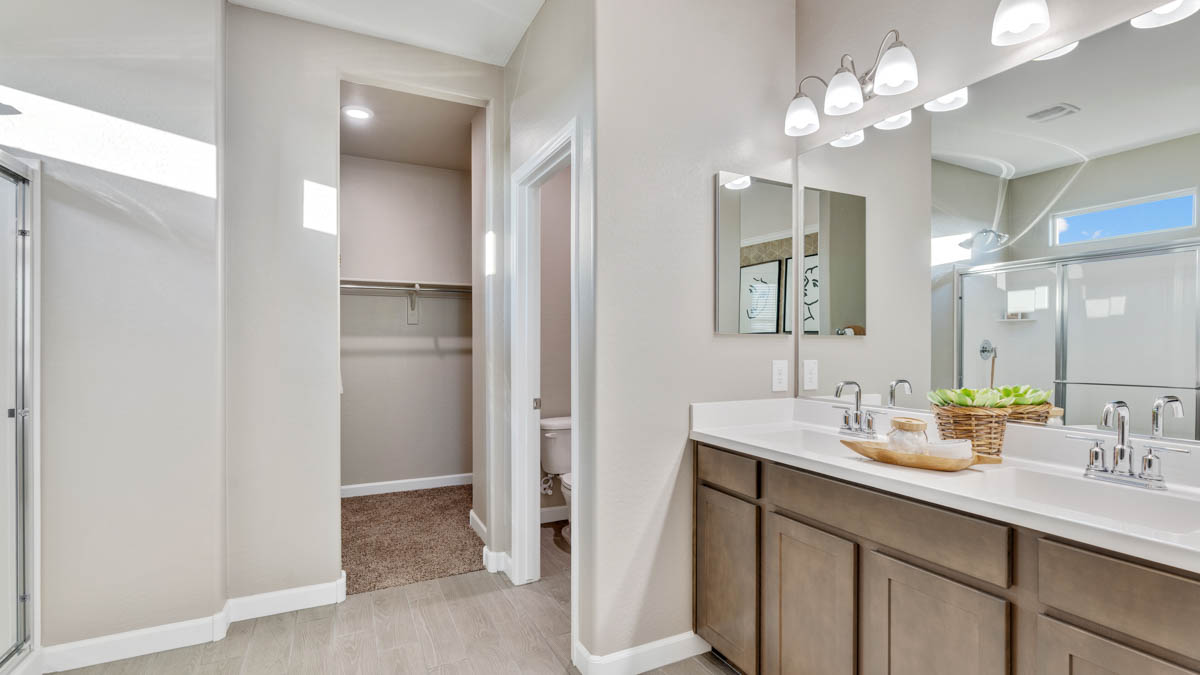 Modern primary bathroom with double vanities, quartz countertops with a walk-in shower and a walk-in closet.
