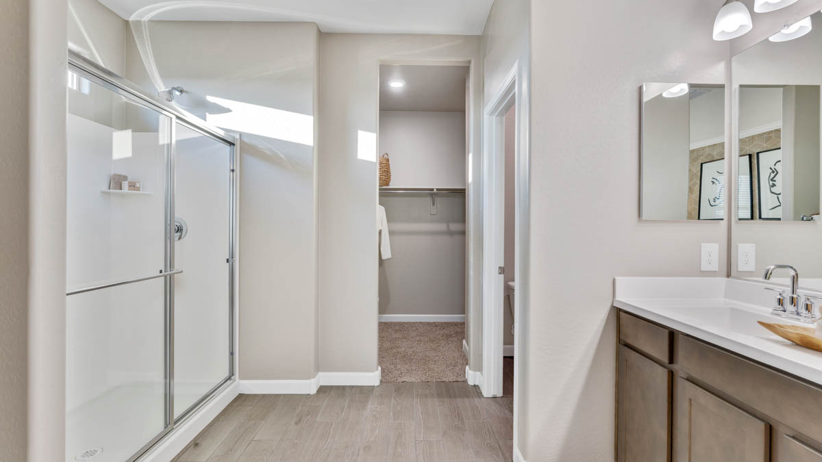 Modern primary bathroom with double vanities, quartz countertops with a walk-in shower and a walk-in closet.