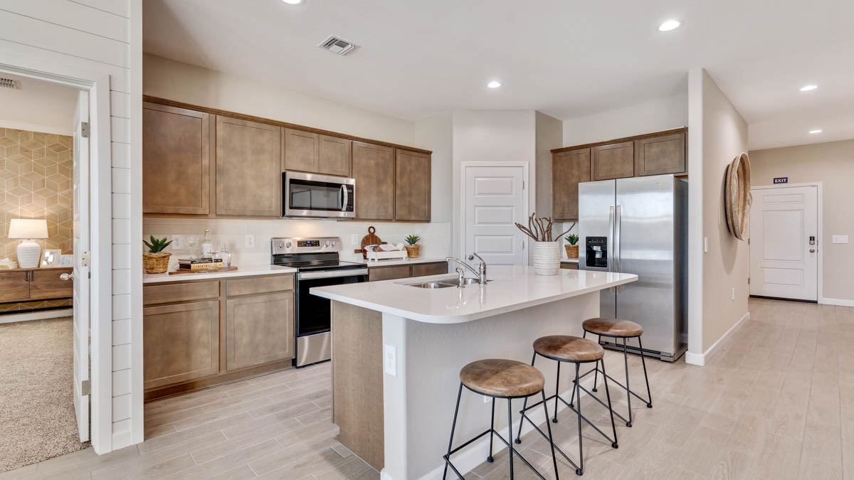 Bright and spacious kitchen with quartz countertops, stainless steel appliances, and an island with bar seating.