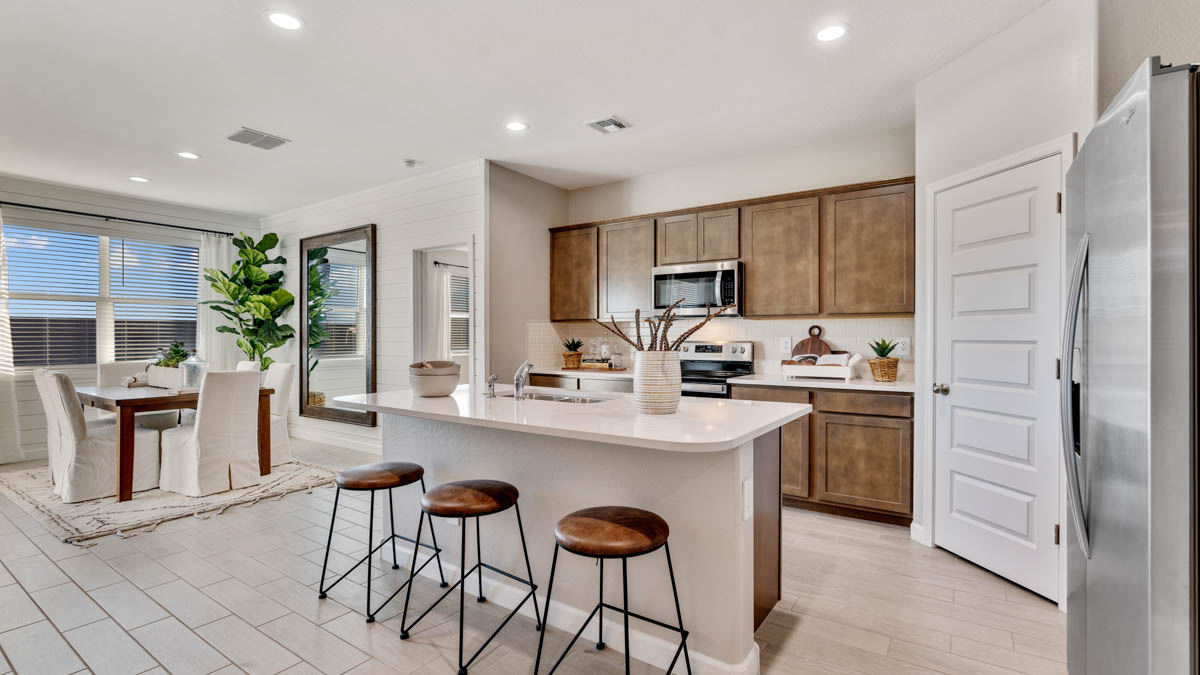 Bright and spacious kitchen with quartz countertops, stainless steel appliances, and an island with bar seating.