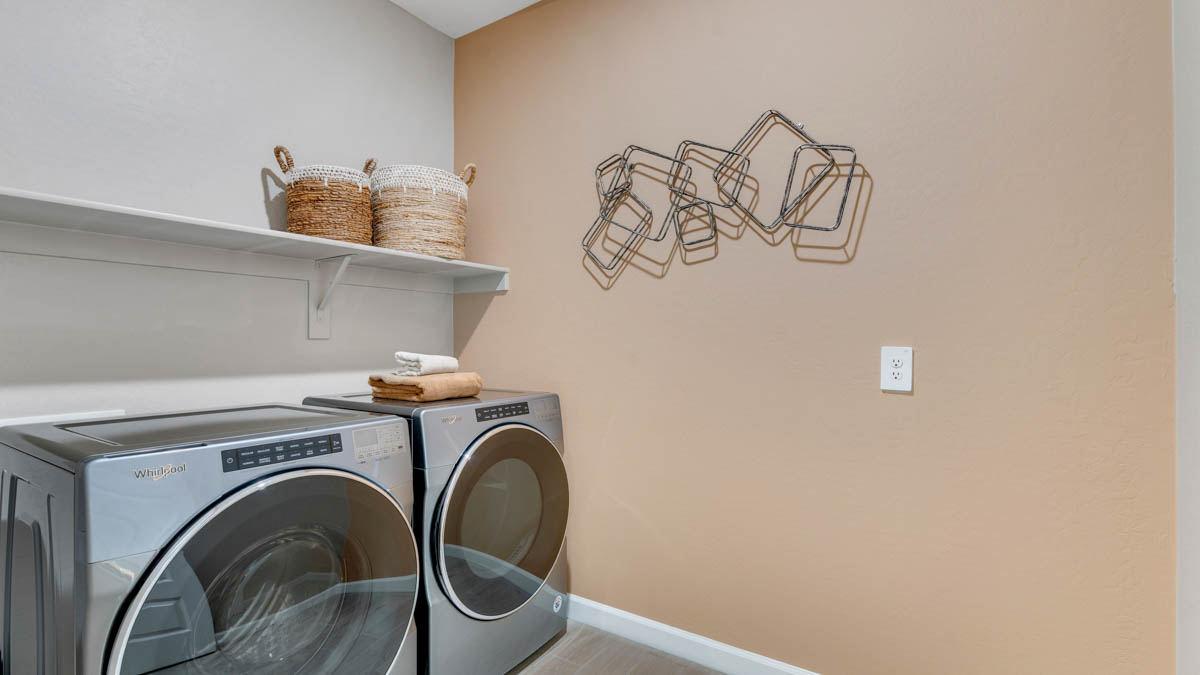 Spacious laundry room with washer and dryer connections and shelving for storage.