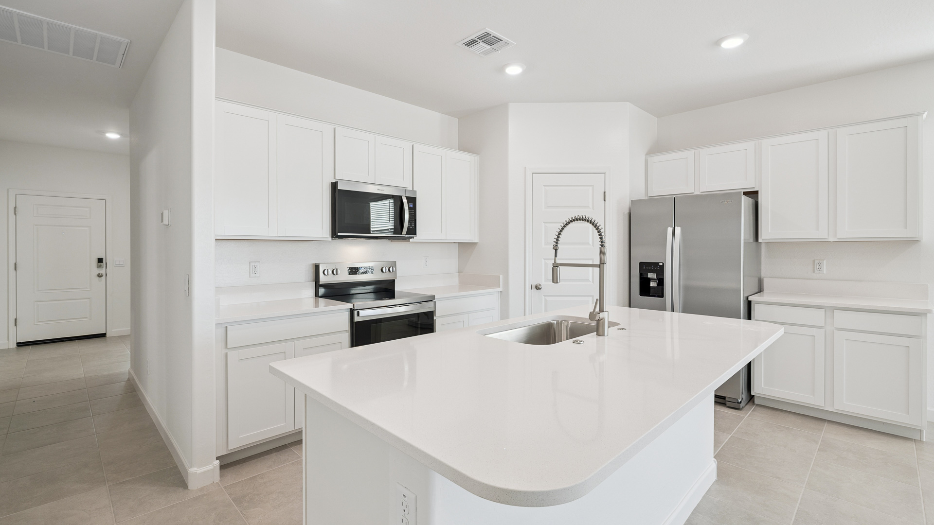 Bright and spacious kitchen with quartz countertops, stainless steel appliances, and an island with bar seating.