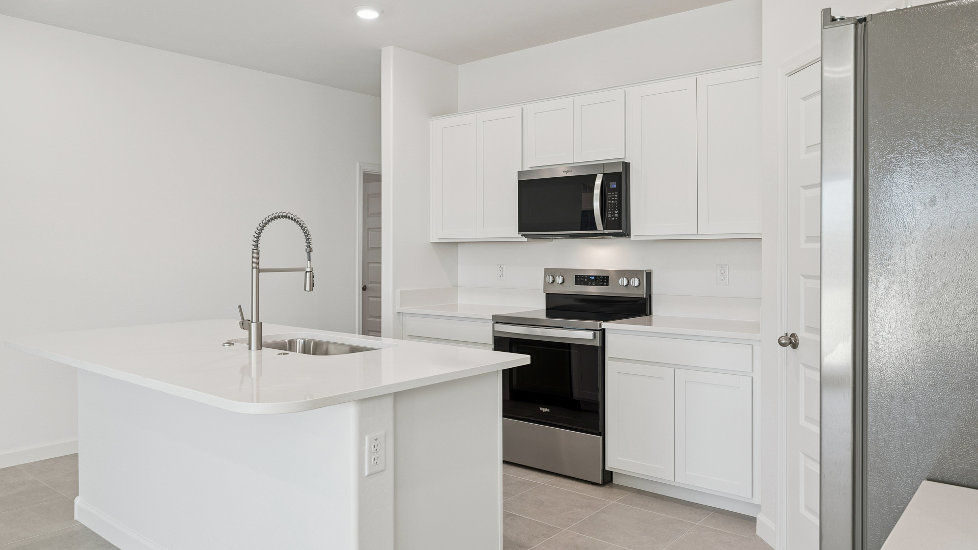 Bright and spacious kitchen with quartz countertops, stainless steel appliances, and an island with bar seating.