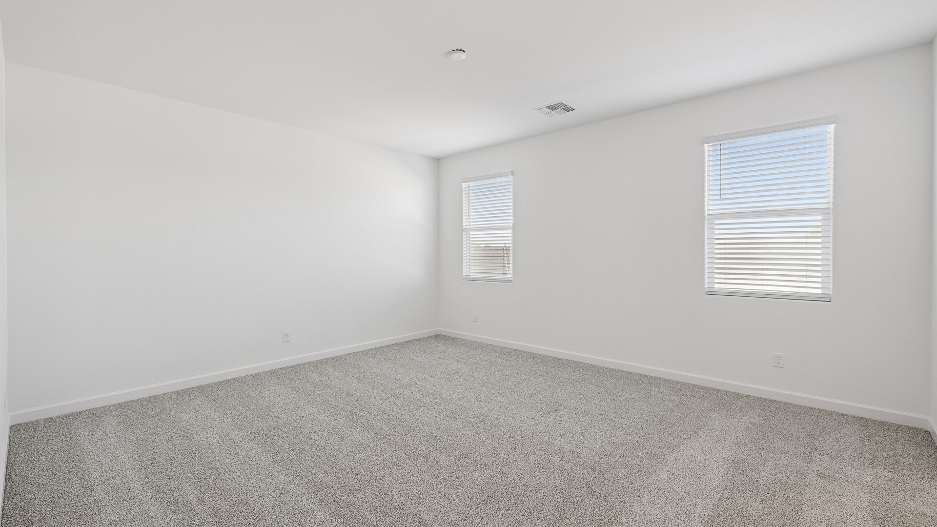 A spacious primary bedroom emphasizing open space and natural lighting.