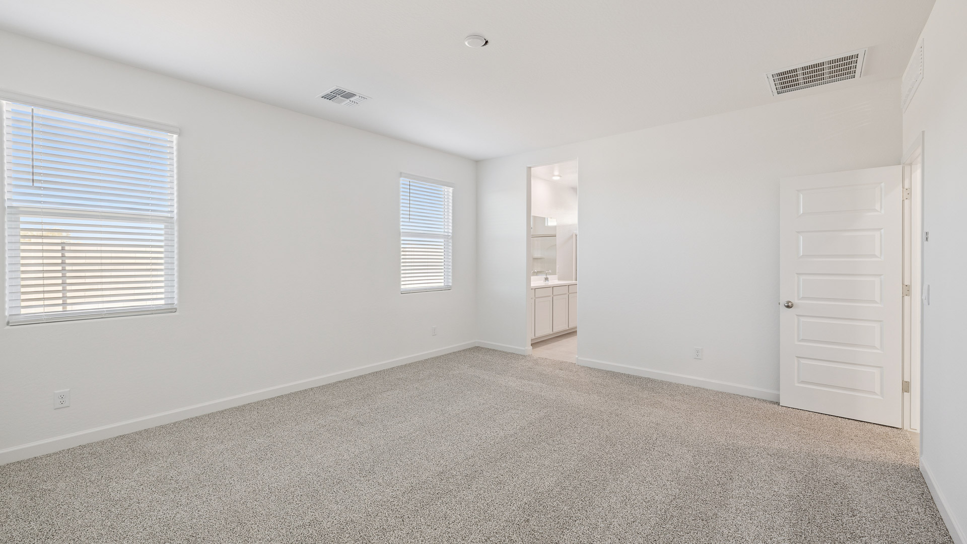 A spacious primary bedroom emphasizing open space and natural lighting.