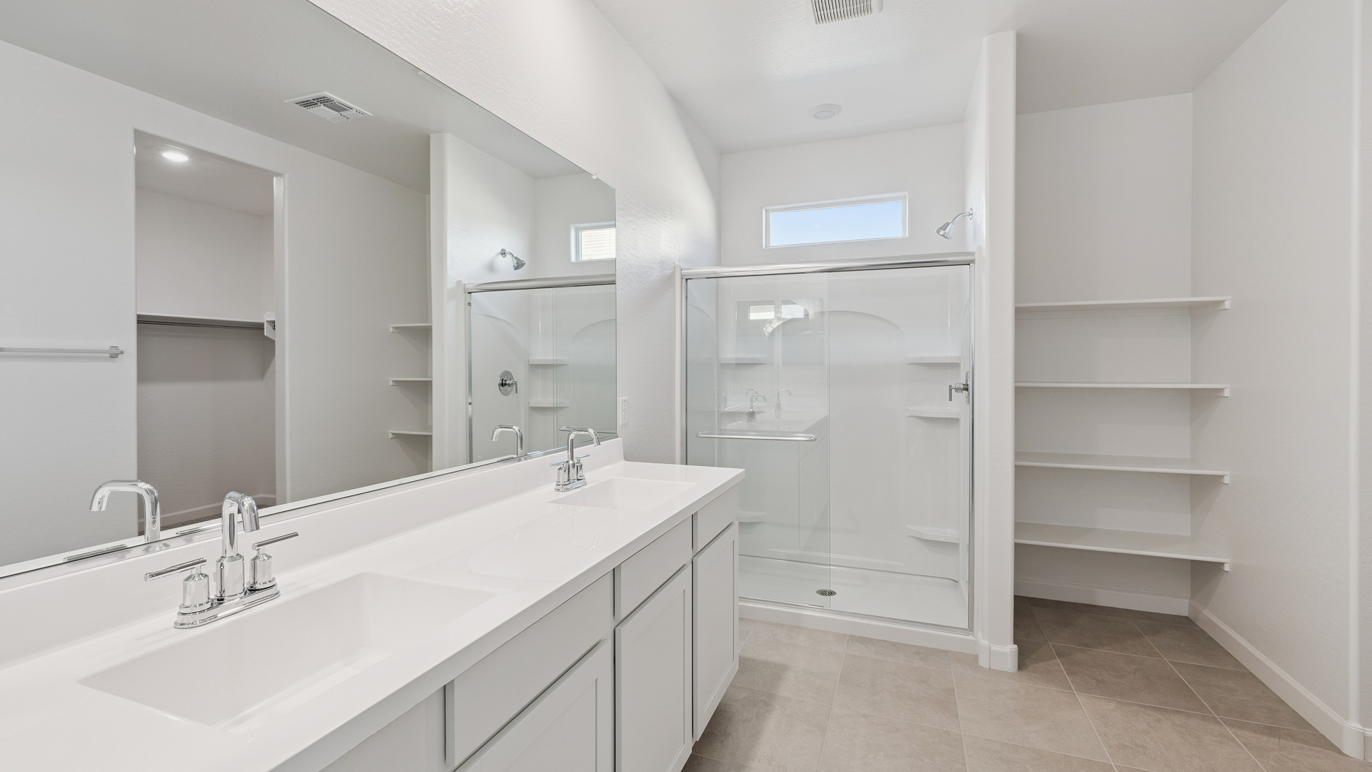 Modern primary bathroom with double vanities, quartz countertops with a walk-in shower and a walk-in closet.