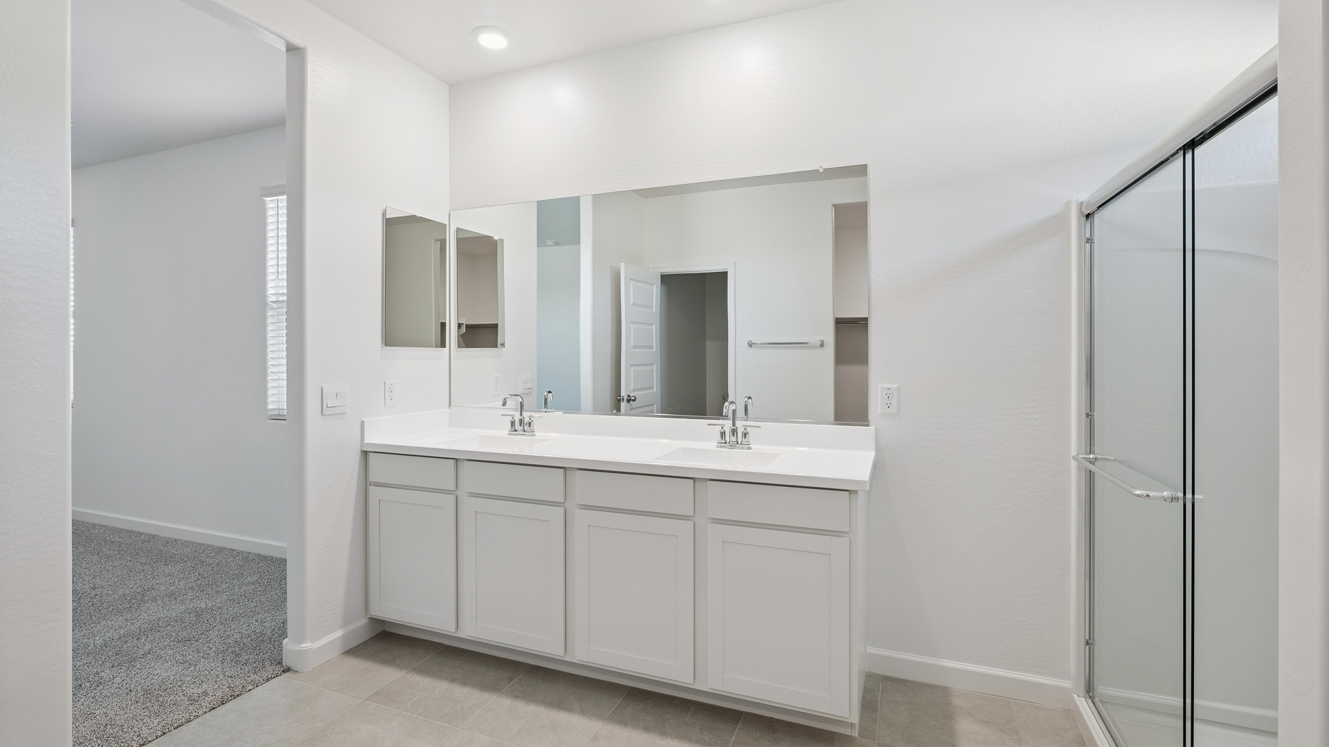 Modern primary bathroom with double vanities, quartz countertops with a walk-in shower and a walk-in closet.