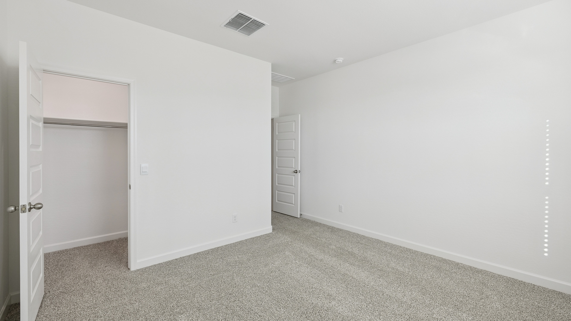 Comfortable guest bedroom featuring neutral-toned walls and a large closet.