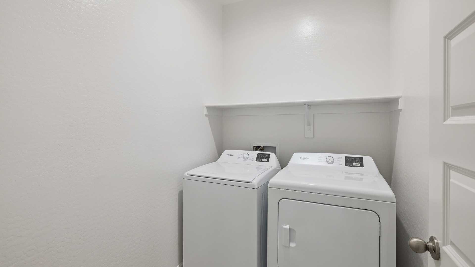 A laundry room featuring a washer and dryer, neatly arranged with ample space for laundry tasks and storage.