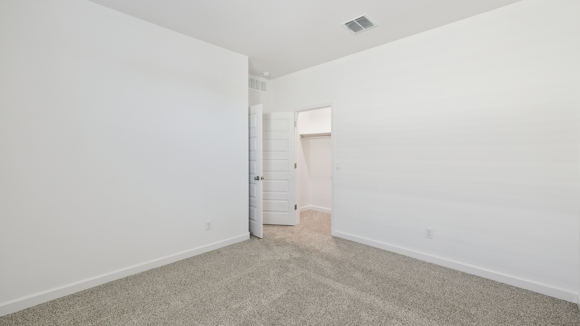 Comfortable guest bedroom featuring neutral-toned walls and a large closet.