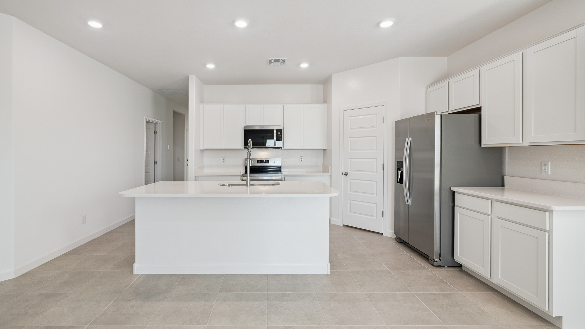 Bright and spacious kitchen with quartz countertops, stainless steel appliances, and an island with bar seating.