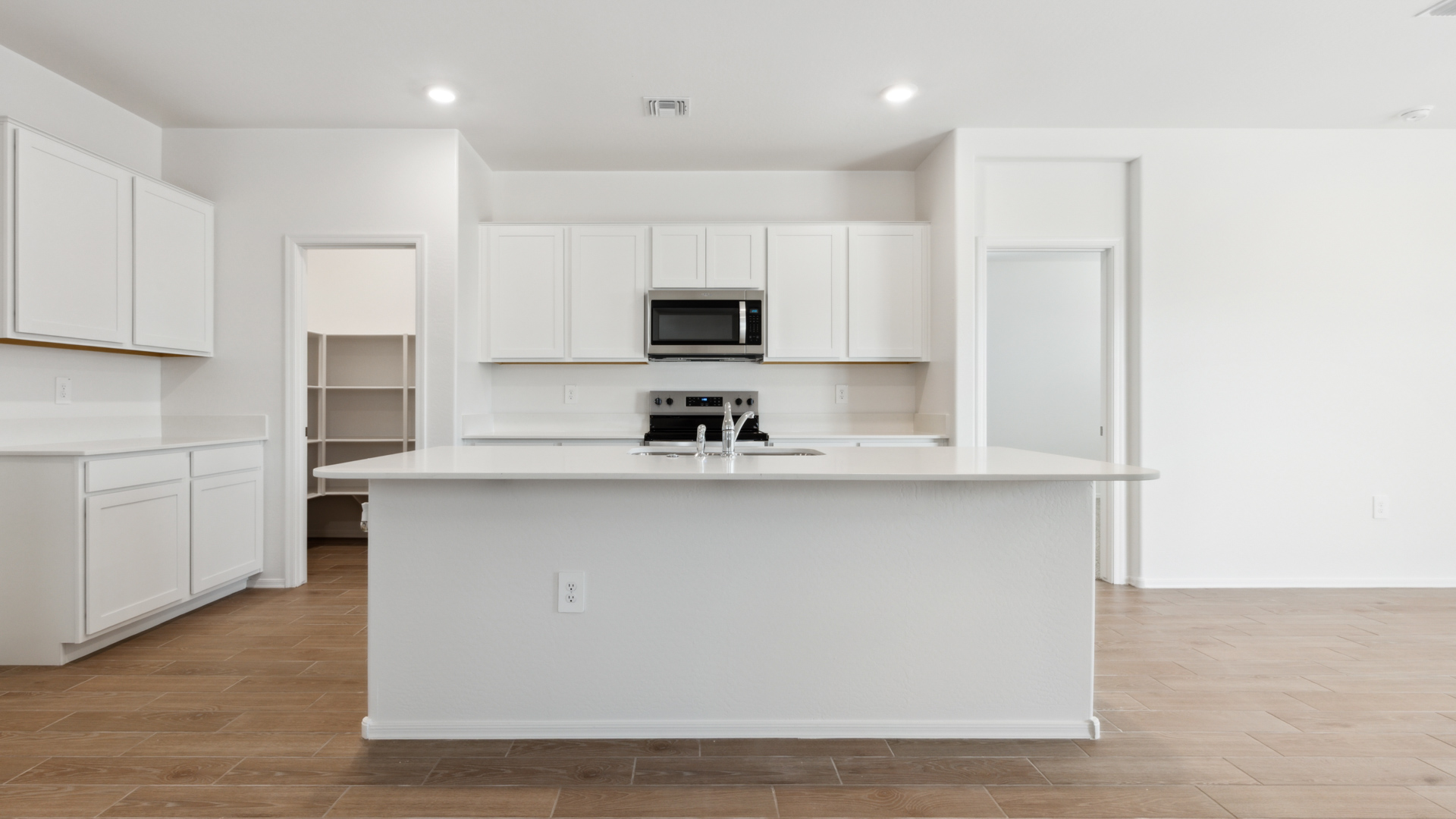 Bright and spacious kitchen with quartz countertops, stainless steel appliances, and an island with bar seating.