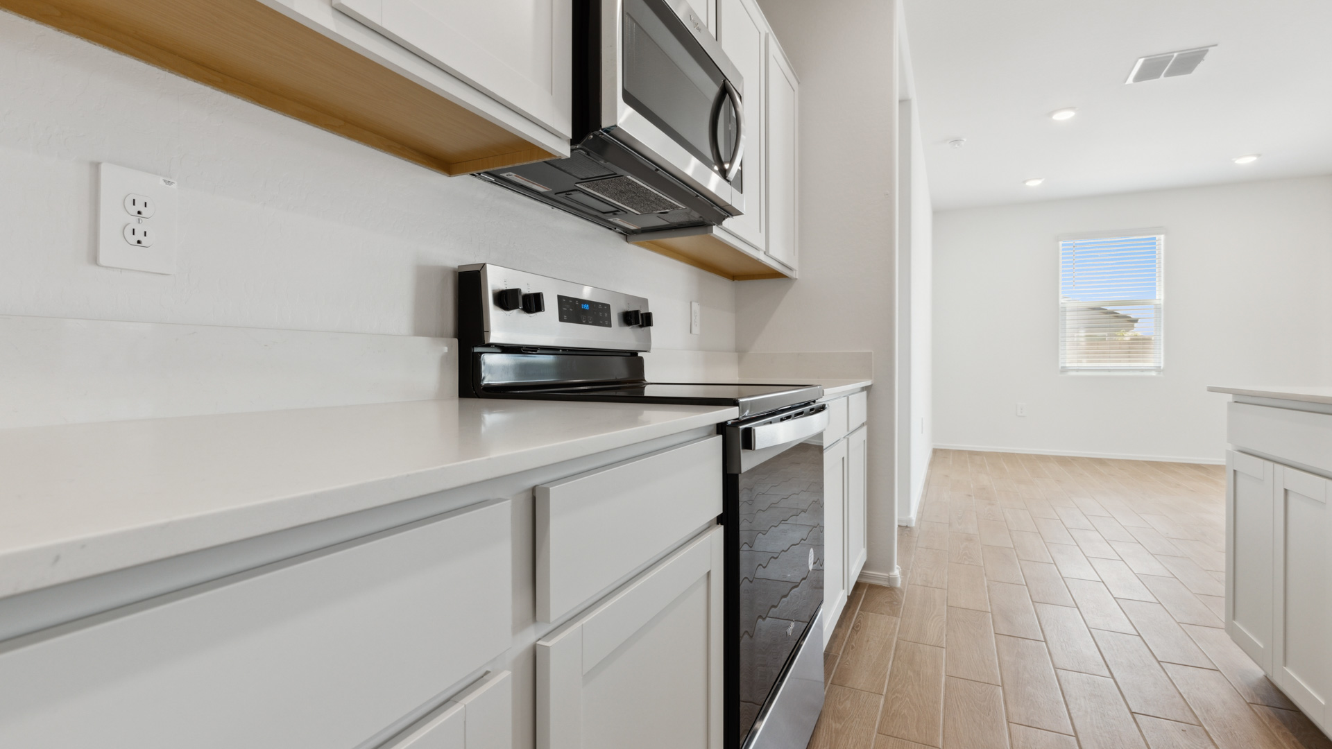 Bright and spacious kitchen with quartz countertops, stainless steel appliances, and an island with bar seating.