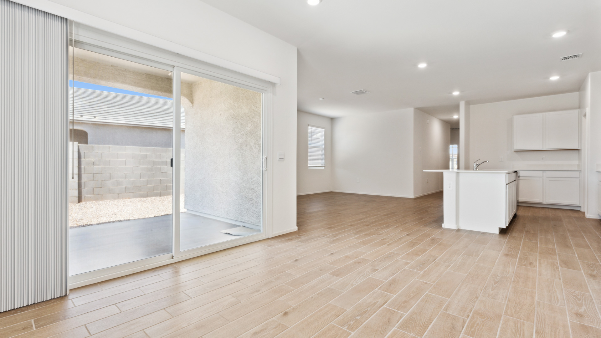 Living and dining room with hard wood flooring and bright windows and sliding doors that leads to the backyard porch.