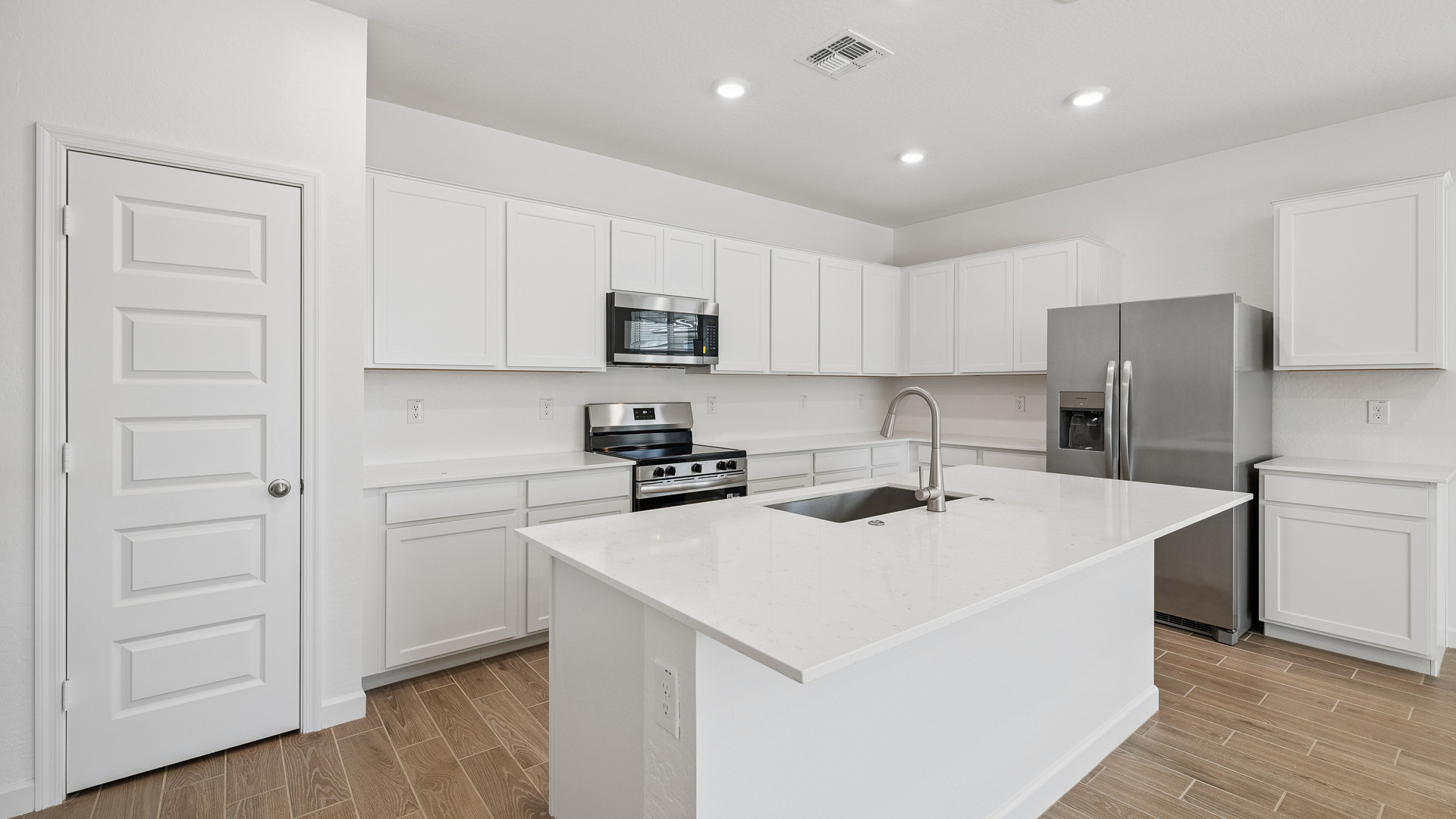 Bright and spacious kitchen with countertops, stainless steel appliances, and an island with bar seating.