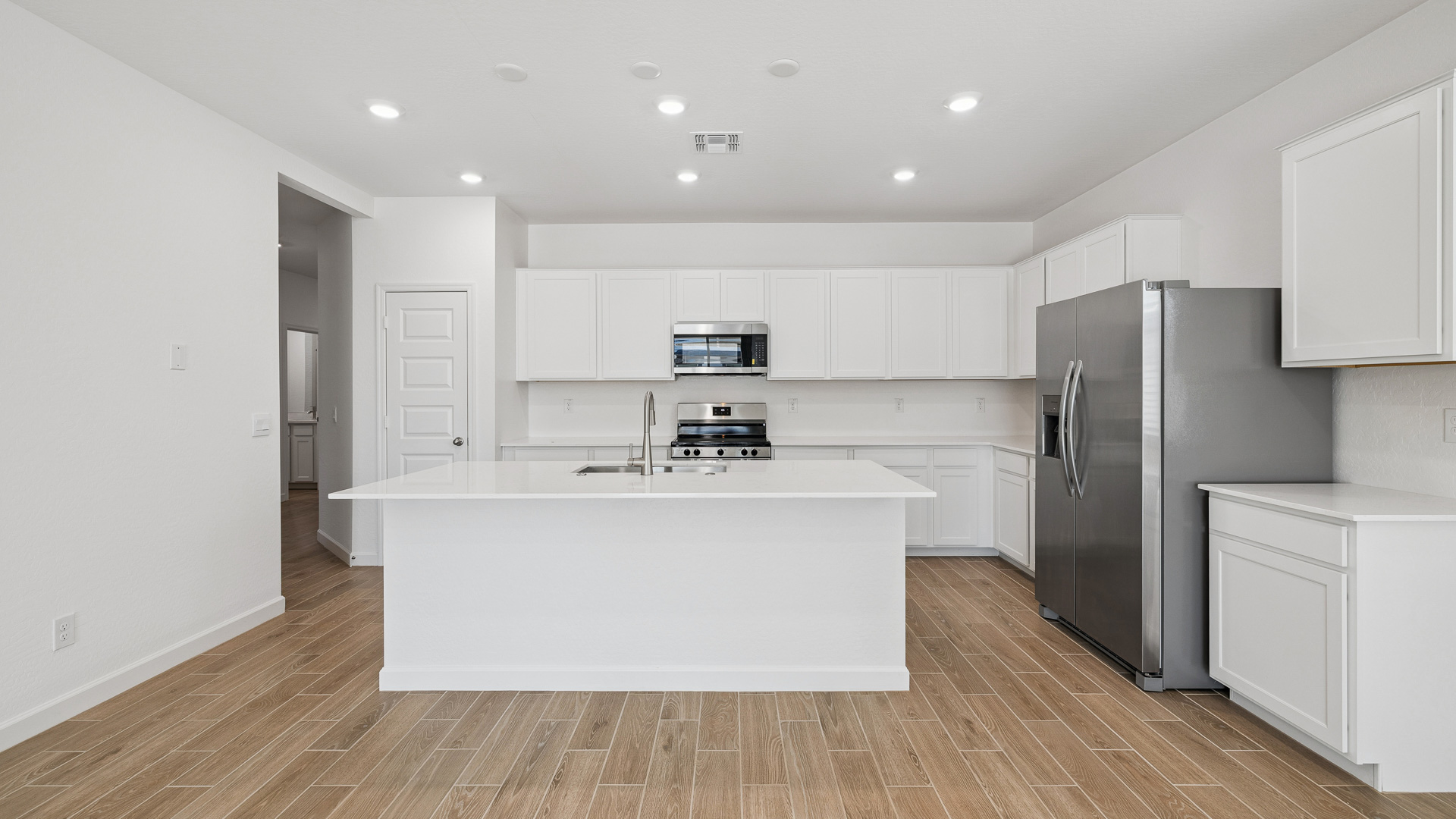 Bright and spacious kitchen with countertops, stainless steel appliances, and an island with bar seating.